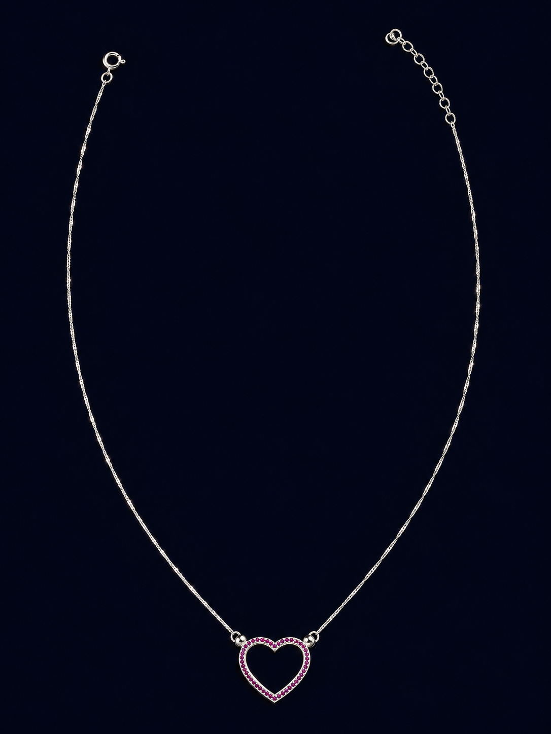 Colar de corrente fina com coração vazado de contorno rosado, ligado à corrente pelas duas laterais superiores.