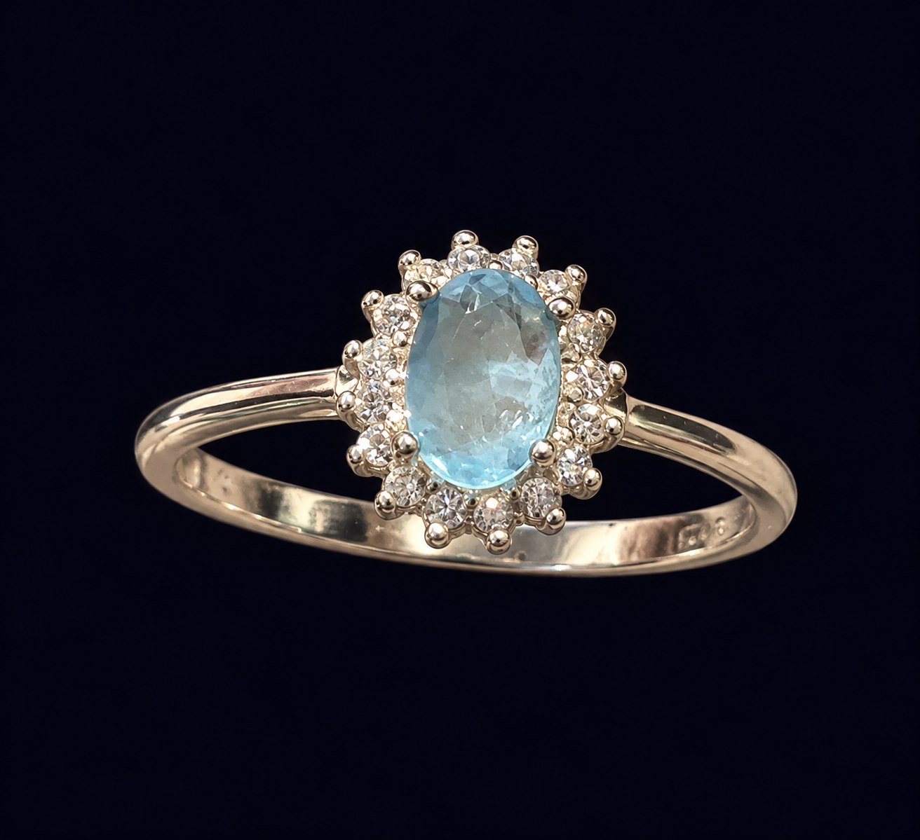 Anel com centro oval azul-claro cercado por detalhes claros.