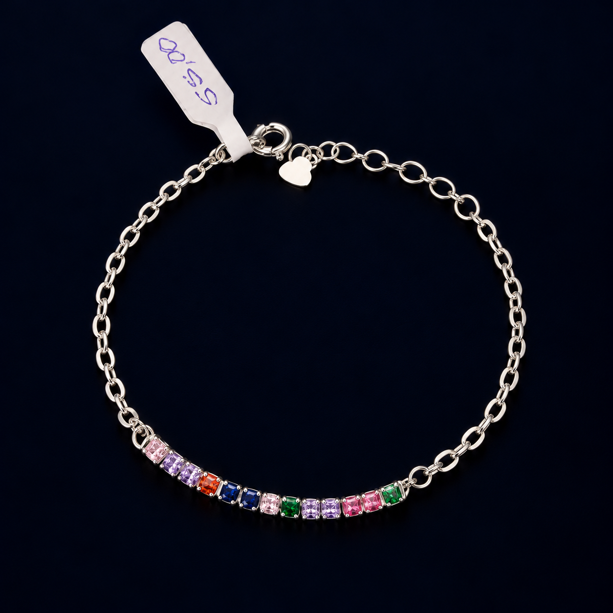 Pulseira de elos alongados com fileira frontal de elementos quadrados multicoloridos sobre fundo escuro.